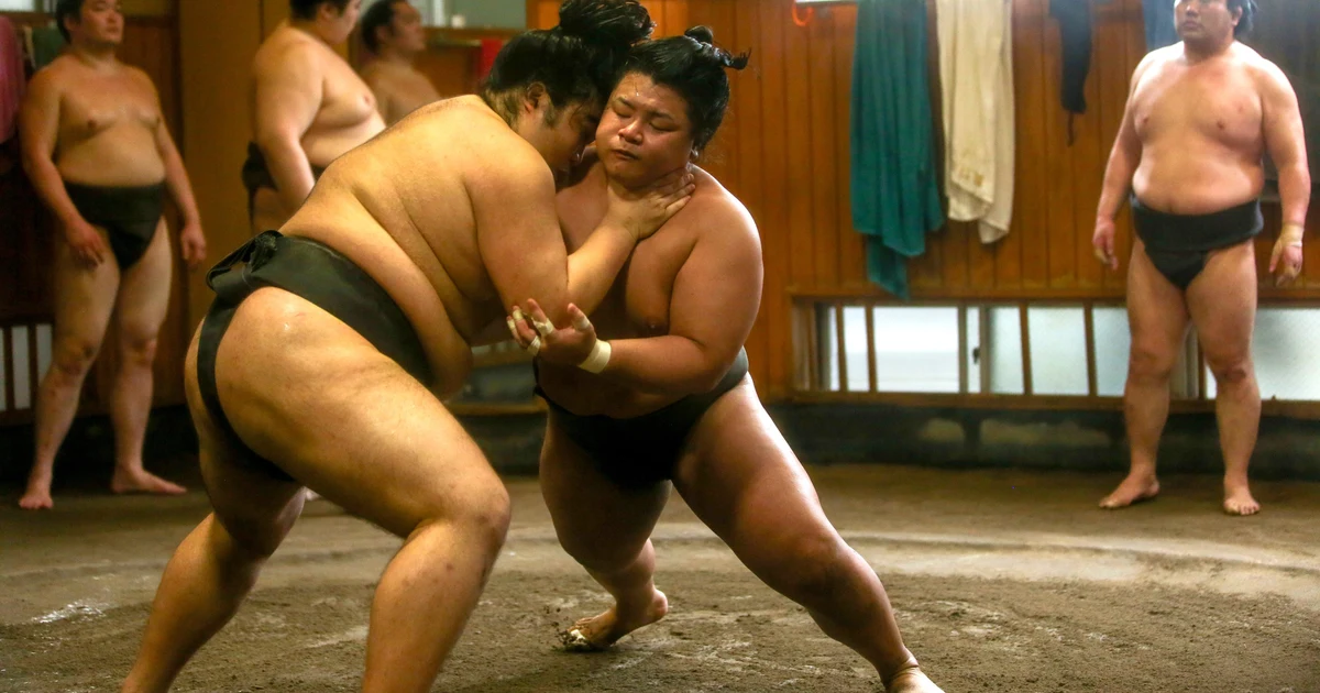 Sumo wrestler practicing at a Tokyo stable, observed by a small group